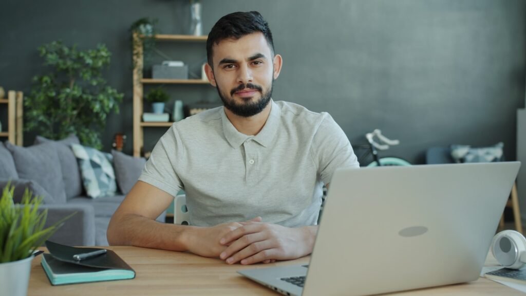 Hombre sentado en un escritorio trabajando con un ordenador portátil